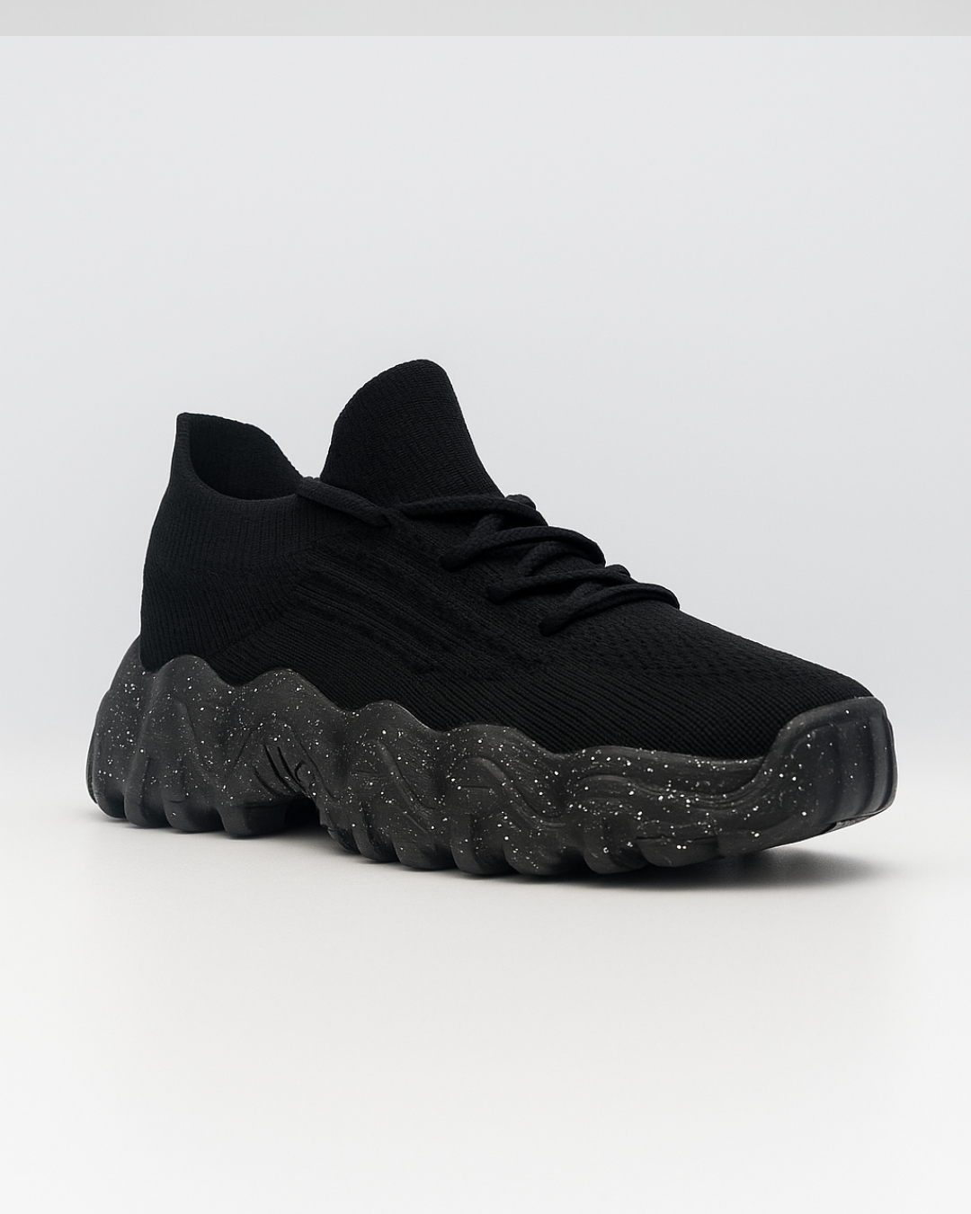 Diagonal view of the black OrthoEase Luxe sneaker facing right, highlighting ergonomic design and textured sole.